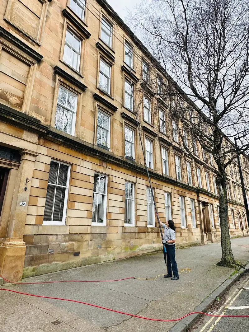 Window cleaner using a water-fed pole on a Glasgow sandstone tenement