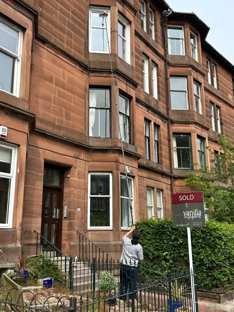 Window cleaner reaching upper floor windows on a Glasgow tenement